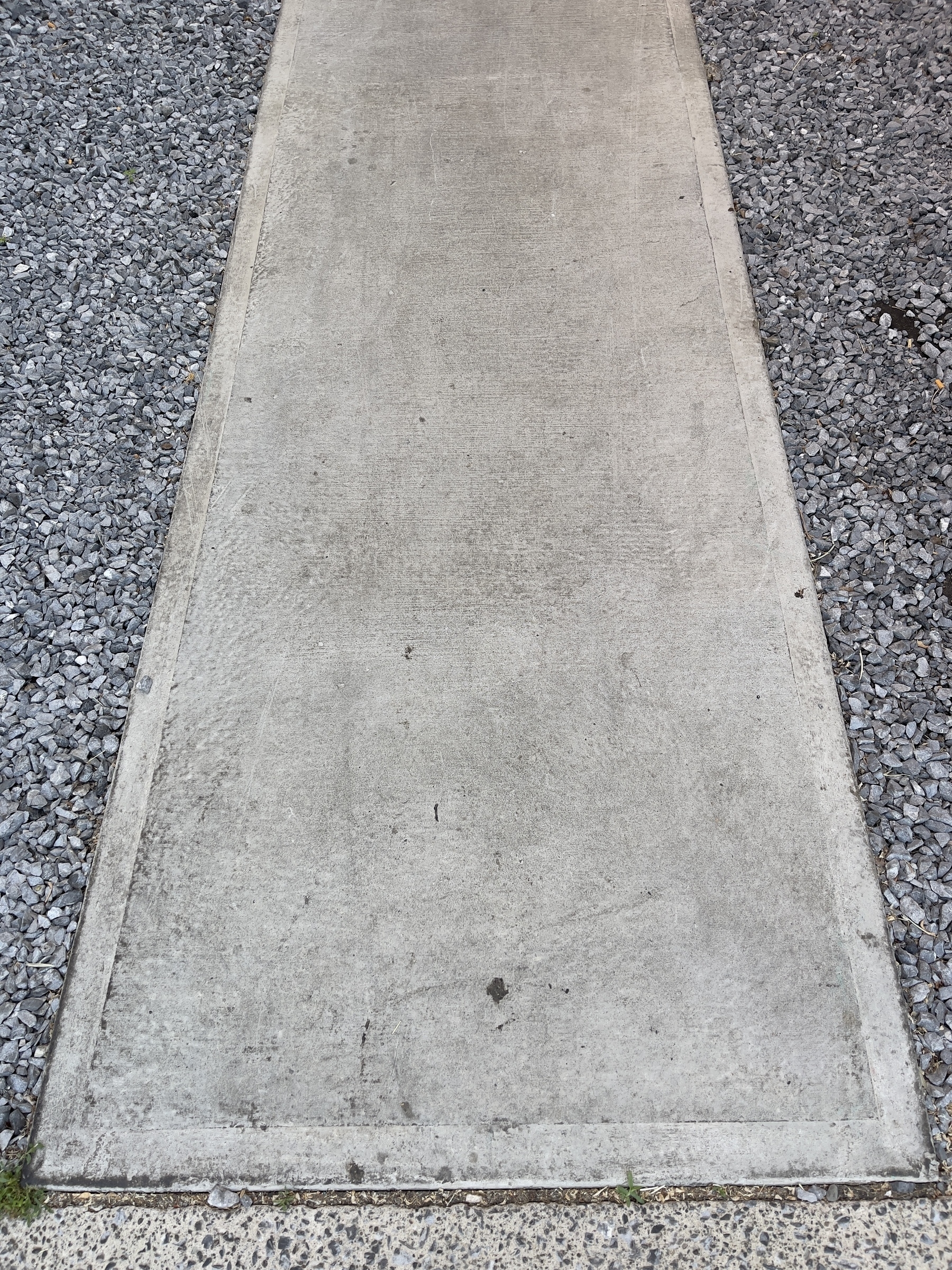 Concrete sidewalk with gravel on the left and right.