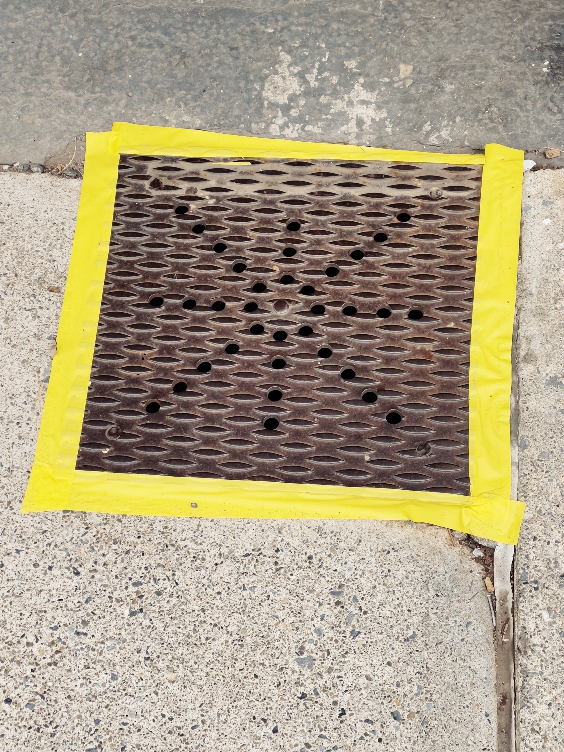 Yellow caution tape around utility access steel plate.