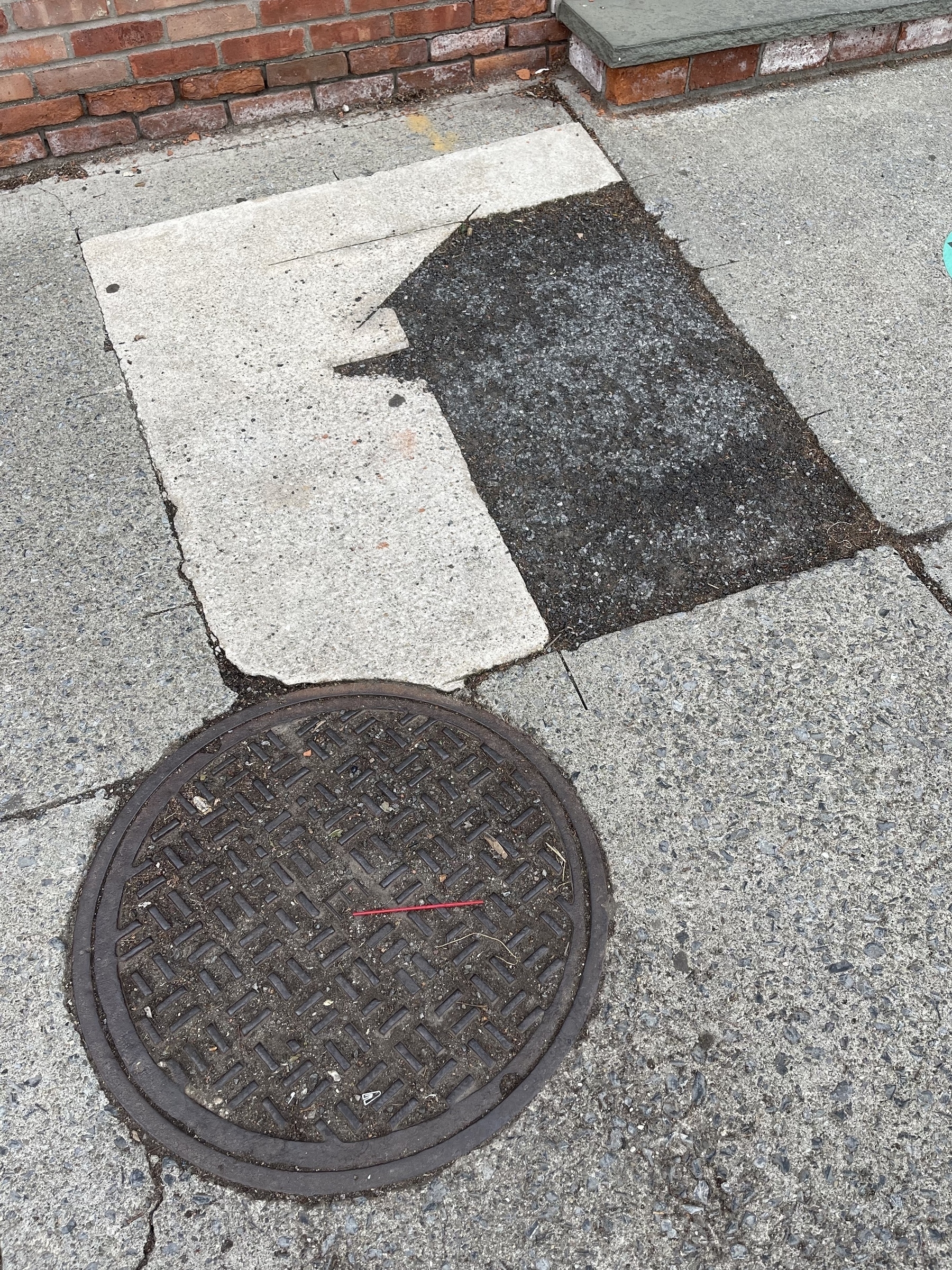 Circle and rectangle composition of manhole cover and sidewalk repair patching.