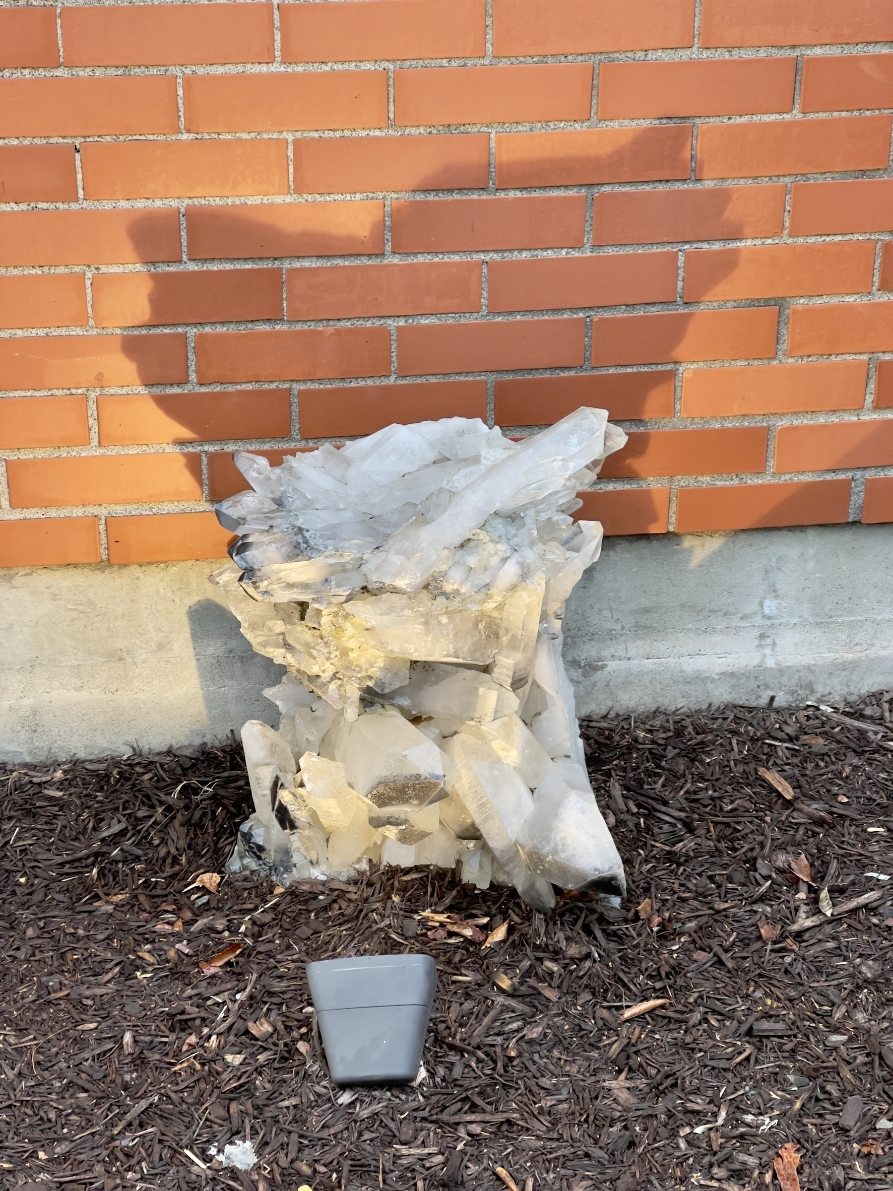 Large mass of crystals with shadow by the brick wall of a building.