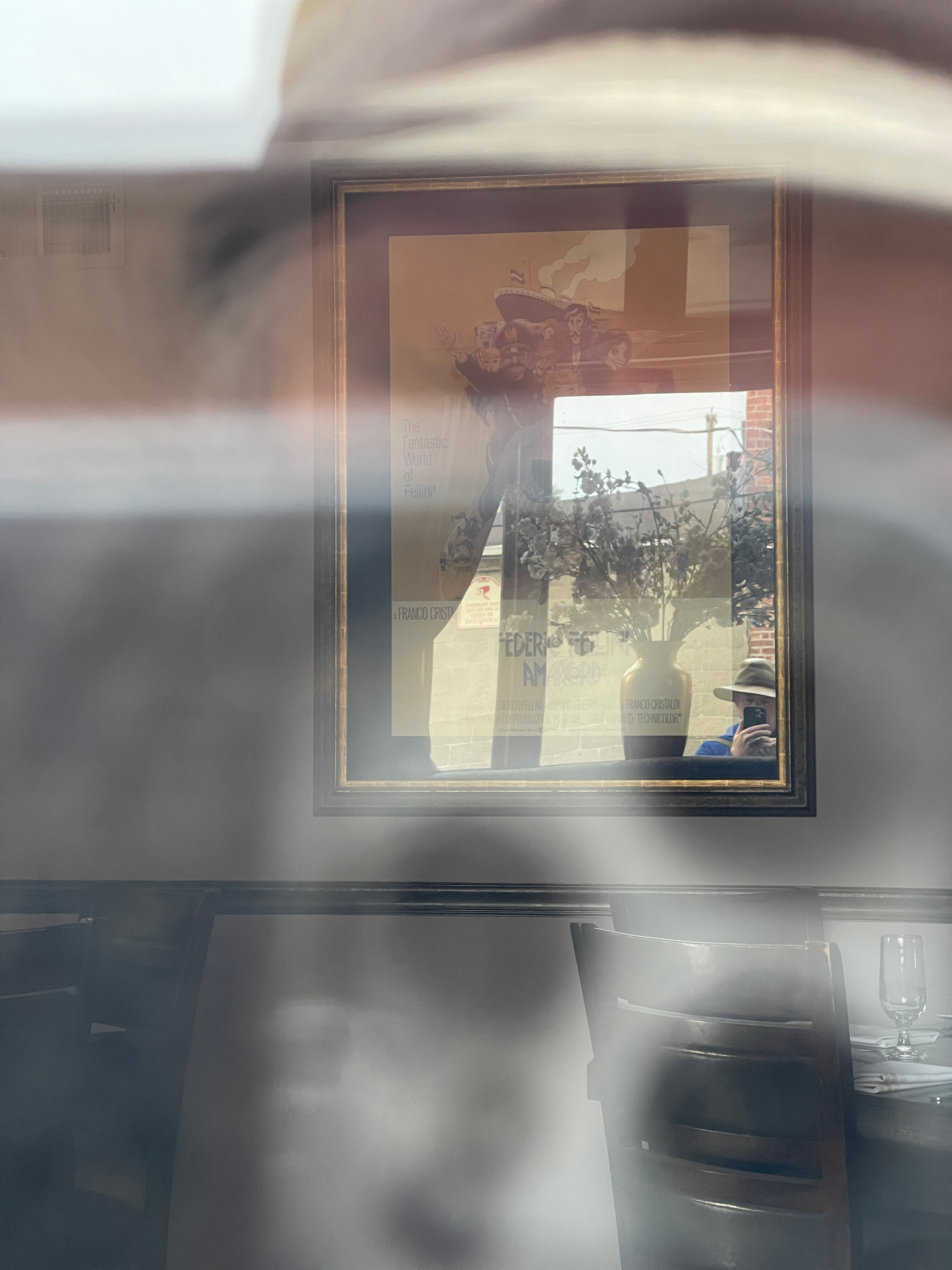 Self reflected in a window and mirror across the room of a restaurant.