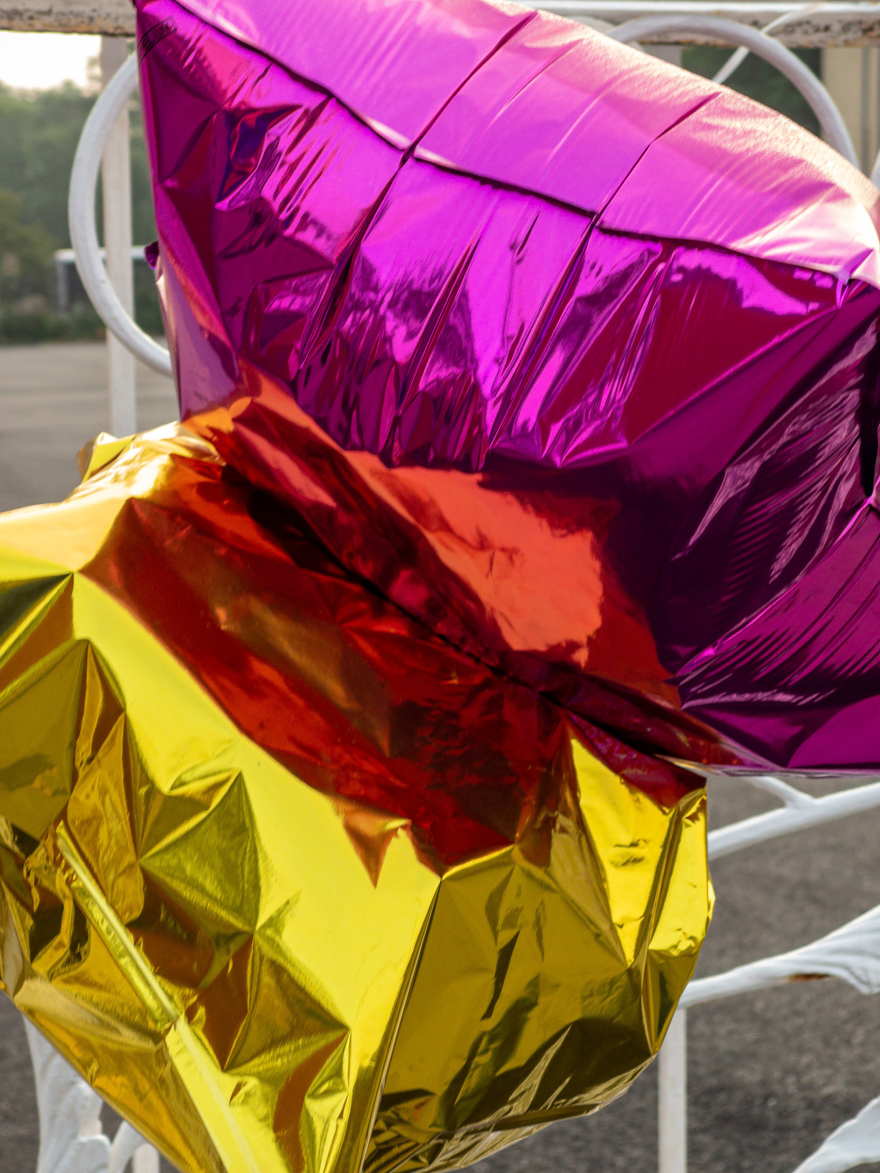 Partially deflated purple and yellow star shaped balloons reflecting off one another to produce an orange hue in the middle.