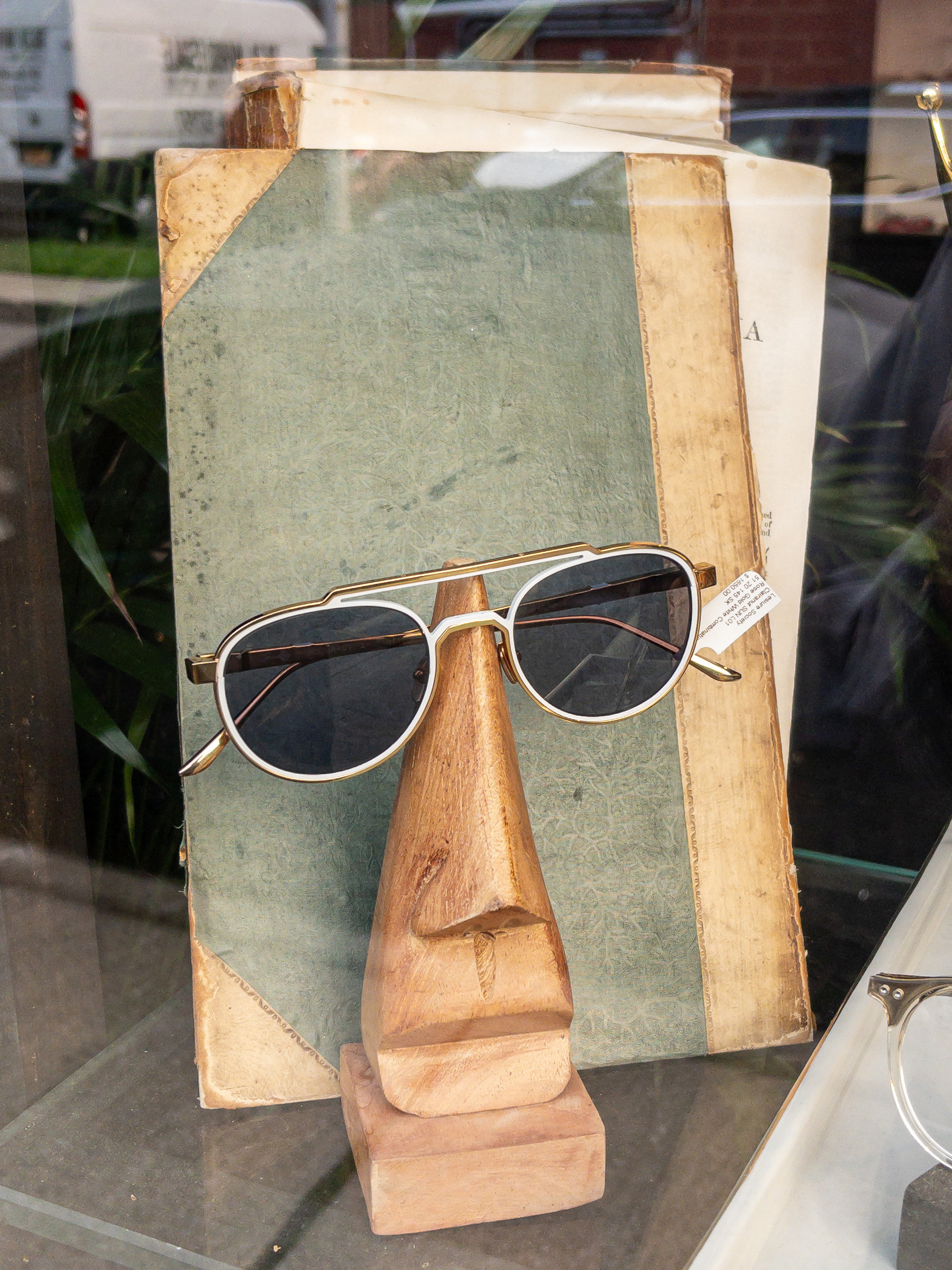 Face made of an old book, sunglasses, wooden nose sculpture, in a shop window.