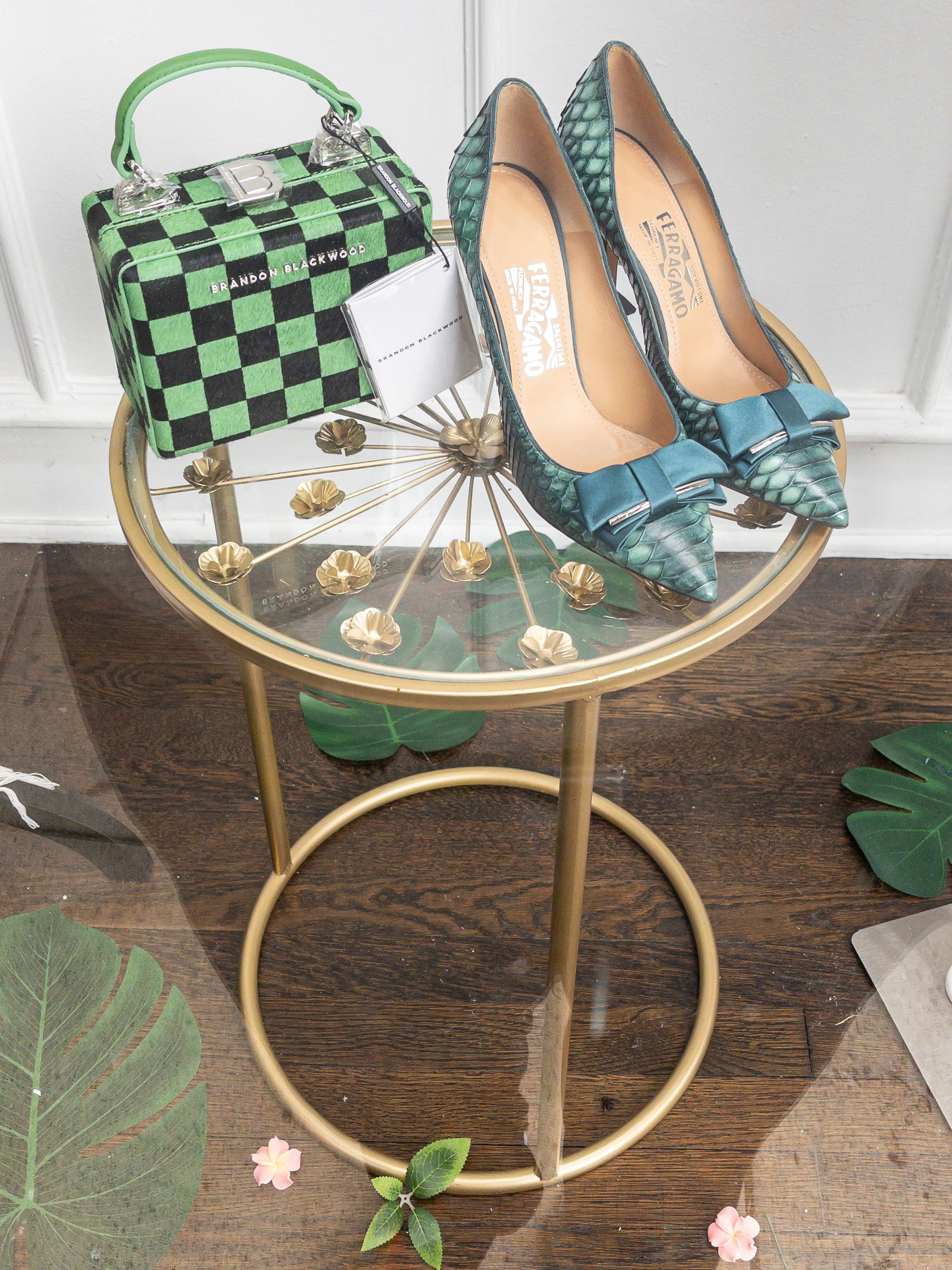 Women’s green shoes and green checkered handbag sitting on an Ilene Gray circles side table in a shop window.