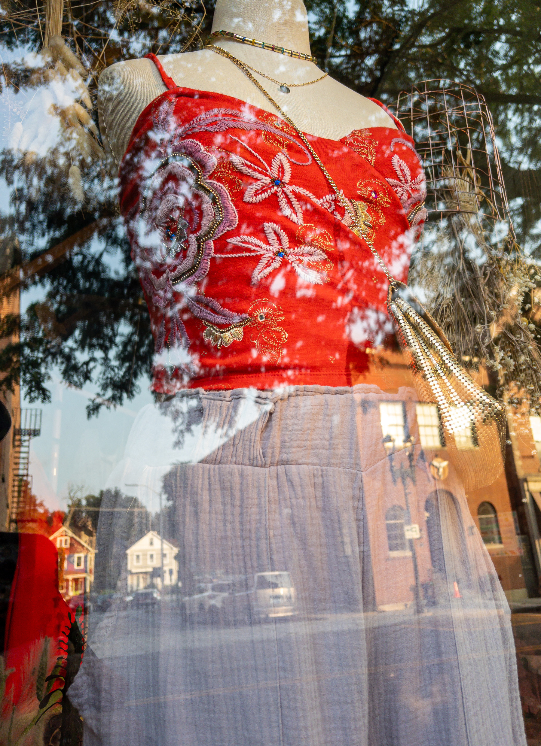 Red embroidered red halter top on an armless and headless mannequin form with blue gray pants.
