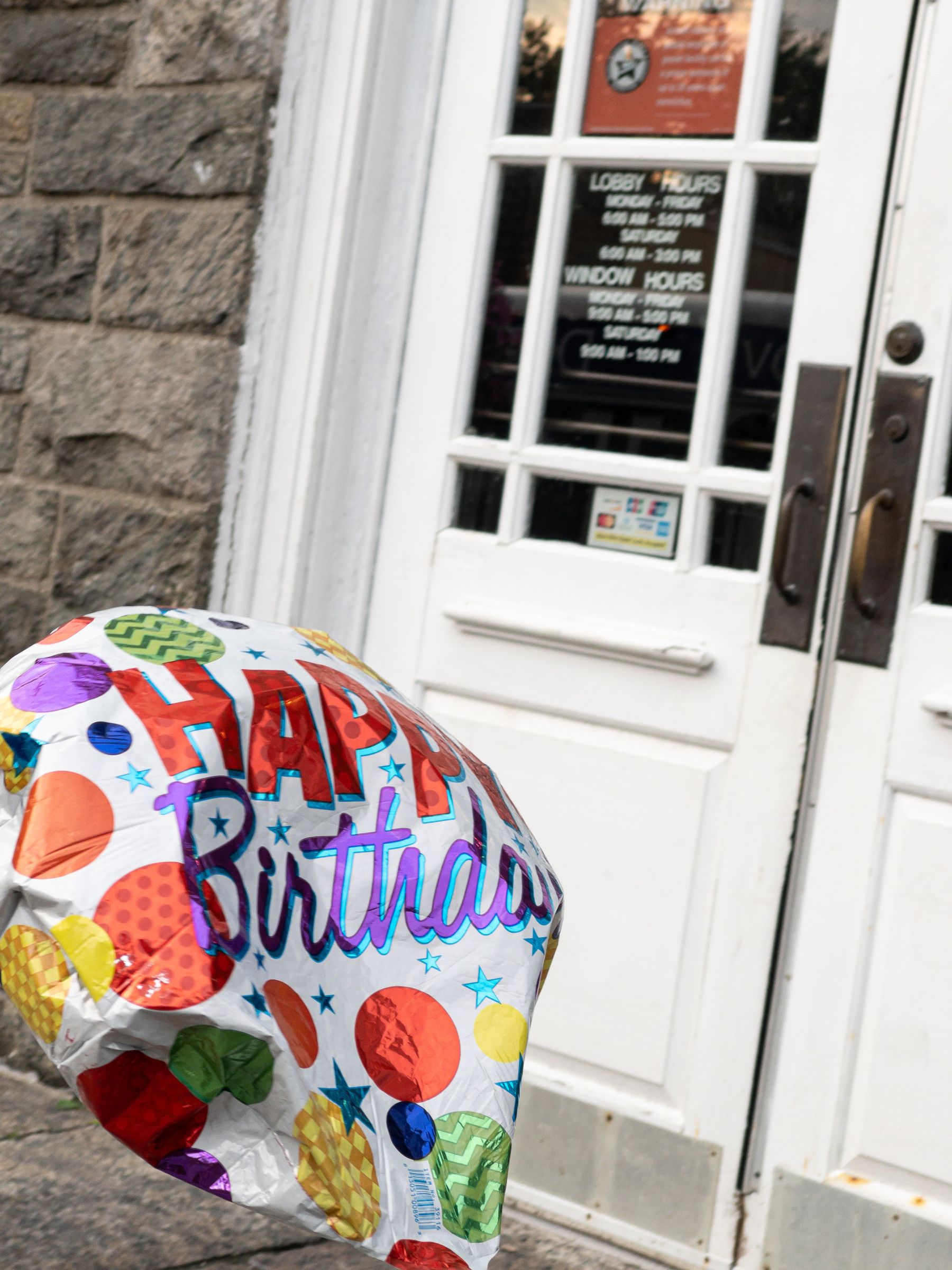 Birthday balloon in lower left corner, bobbing in front of post office doors.