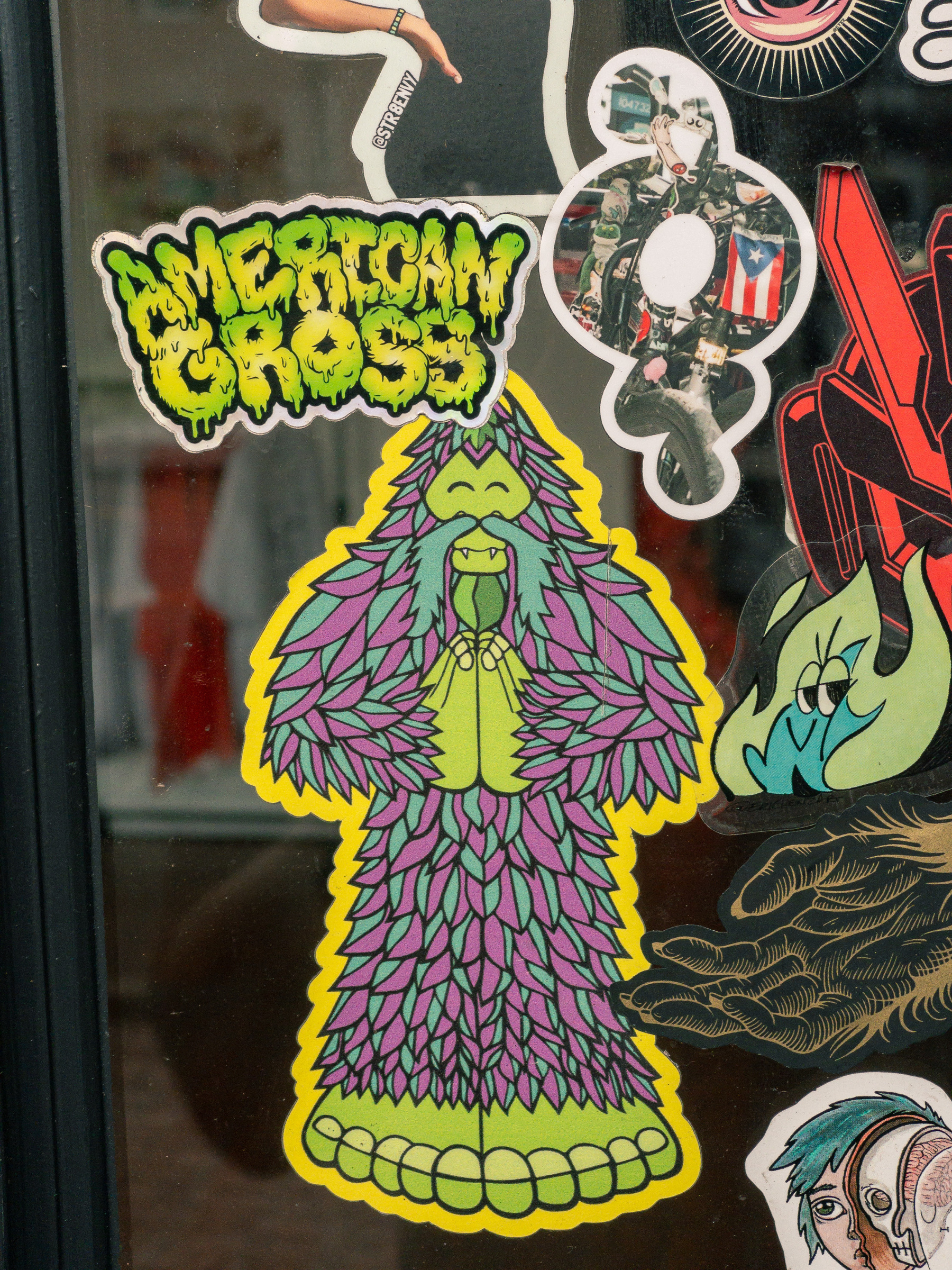 stickers on a window, the main subject is a yeti type monster with the words “american gross” in a banner at the top