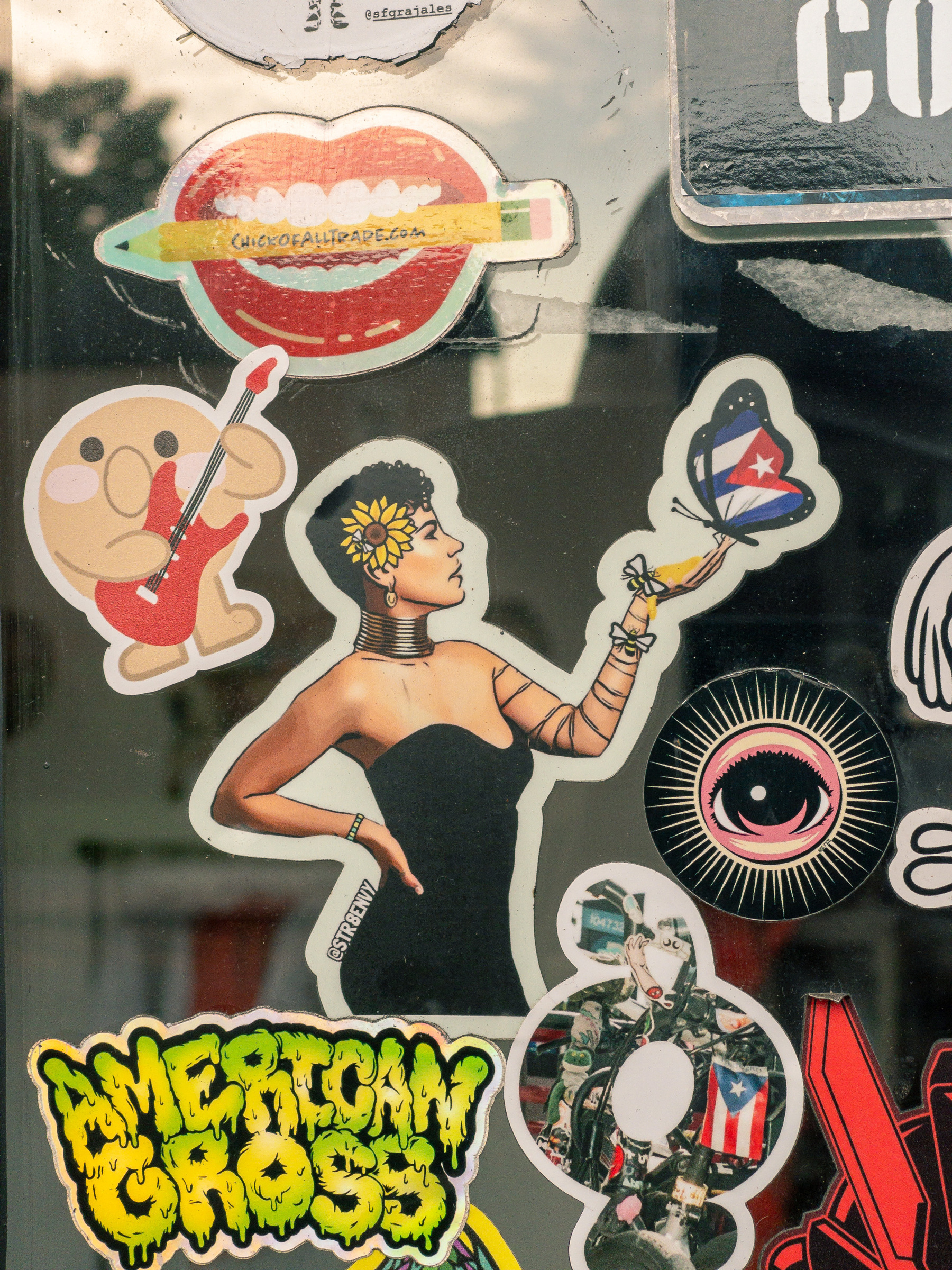 stickers on a window the main subject is a woman in a black sleeveless dress holding up her hand to a butterfly with wings in a Puerto Rican flag motif