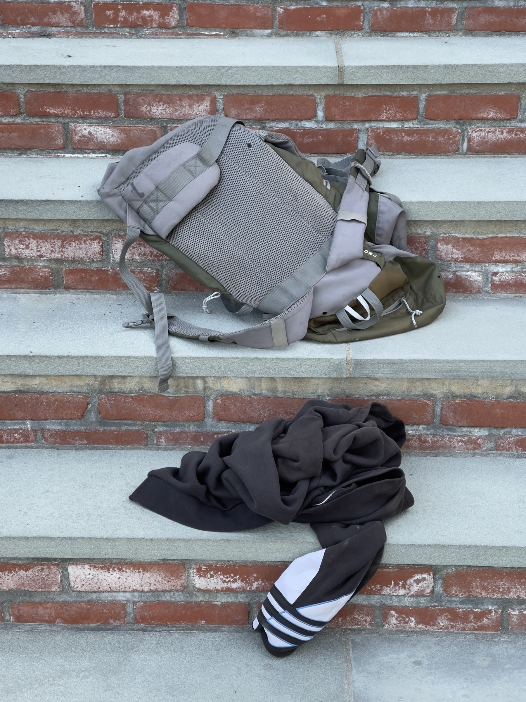 Backpack and jacket tossed onto stone and brick steps.