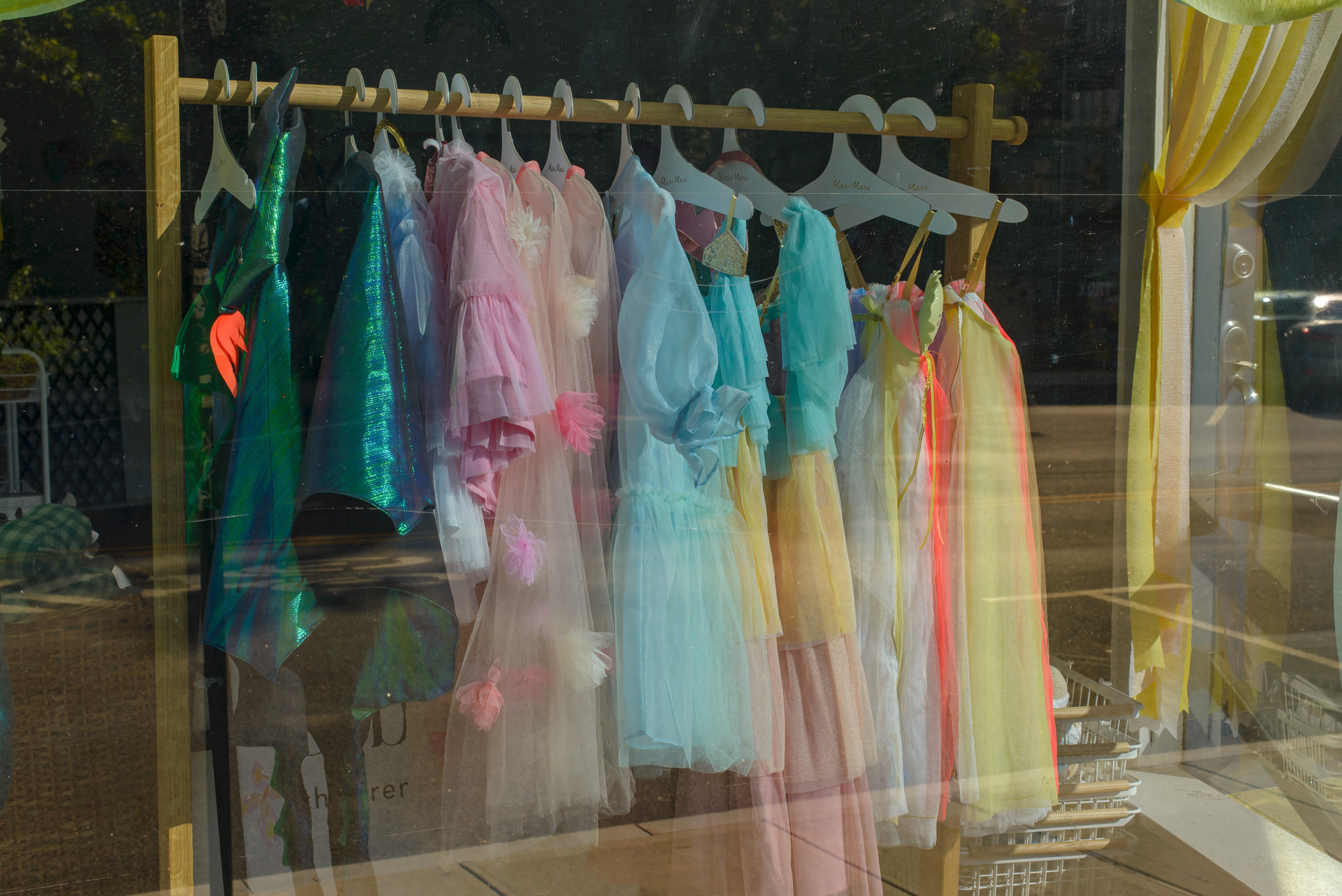 children’s fancy dresses in a range of pastels hanging on a rack in a children’s boutique
